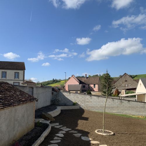 Créations du muret en pierre ainsi que d'un  l'escalier, suivis d'un apport de terre végétale pour les futures plantations puis engazonnement avec pose d'un pas japonais.